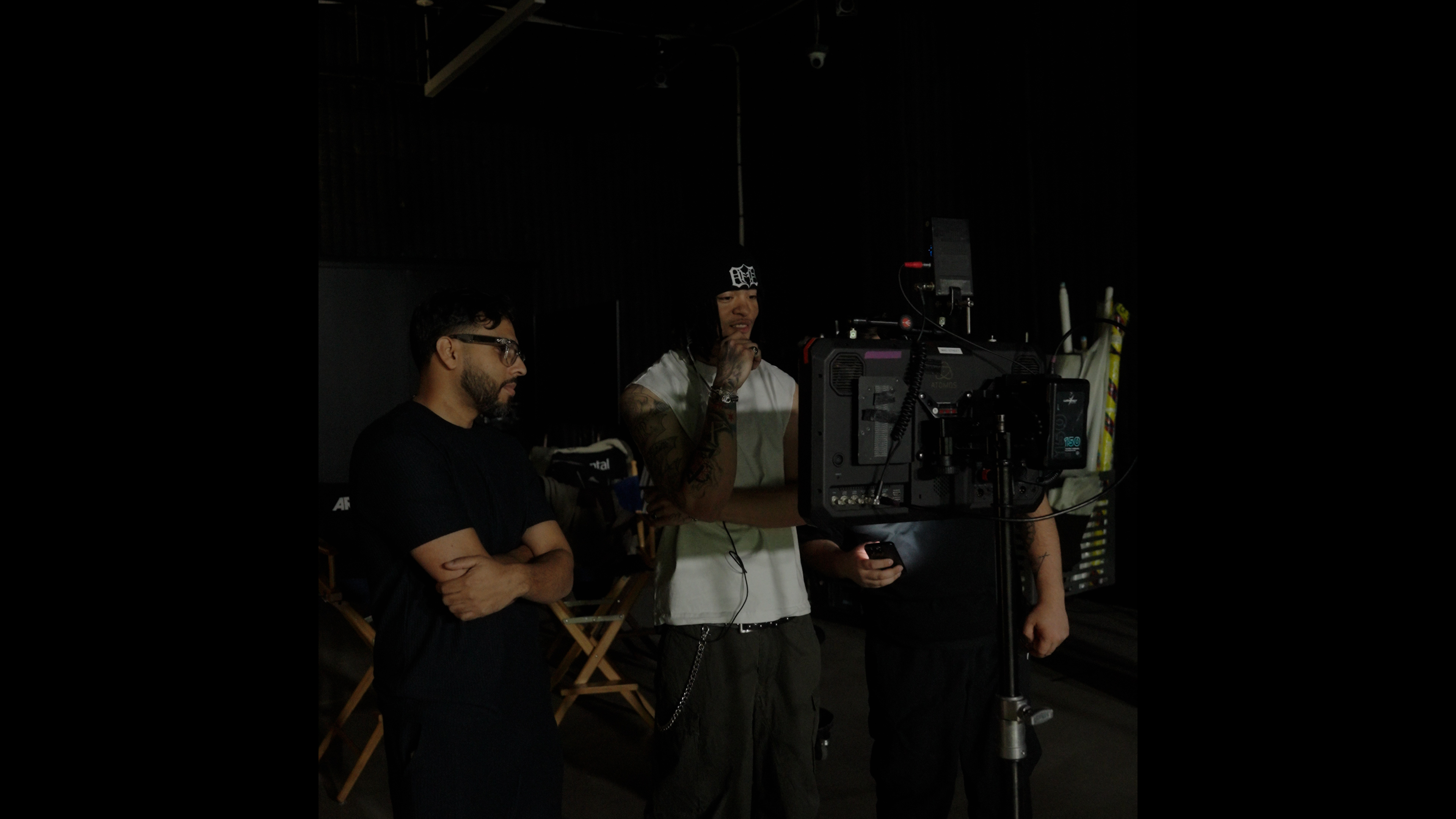 Director and artist watching playback on the monitor beside the camera, low light on set